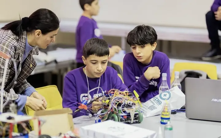 Armathians and a mentor building robots at an ArmRobotics table