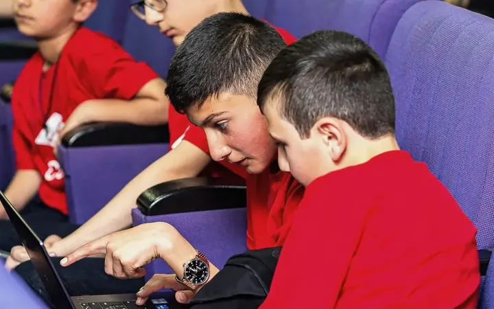 Two DigiCode participants coding on a laptop