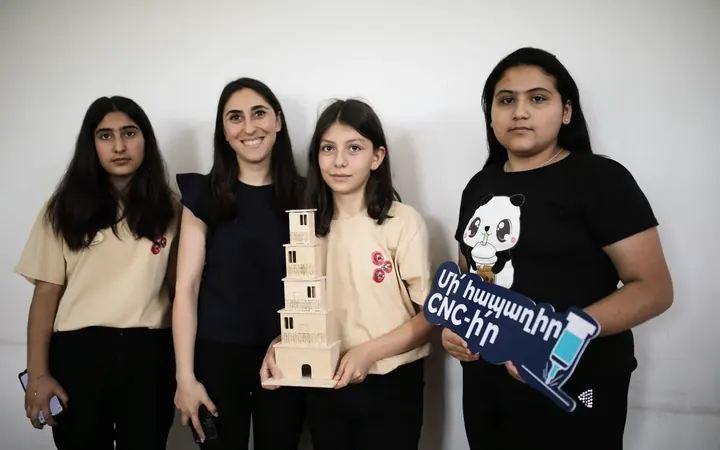Participants holding a wooden tower model and a CNC sign