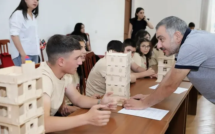 A mentor reviewing wooden models with participants